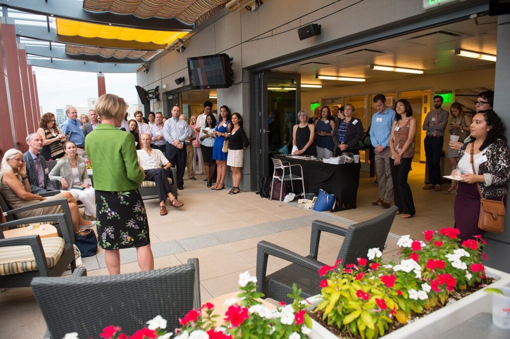 2016 Whole gang: Members and guests listen to Kelly Brilliant, the Executive Director of the Fenway Alliance, talk about upcoming events.